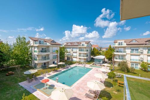 einen Luftblick auf einen Pool mit Sonnenschirmen und Apartmentgebäuden in der Unterkunft Belek Deluxe Suit in Belek