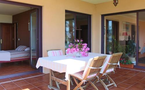 een witte tafel met stoelen en bloemen op een patio bij Espectacular casa a dos minutos de Playa America in Nigrán
