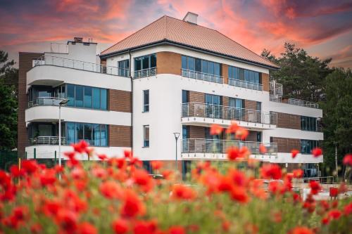 a building with red flowers in front of it at 2HomeRent Baltica Heaven in Rogowo