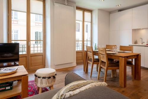 ein Wohnzimmer mit einem Tisch und einer Küche in der Unterkunft ANNAPURNA Annecy Rent Lodge in Annecy