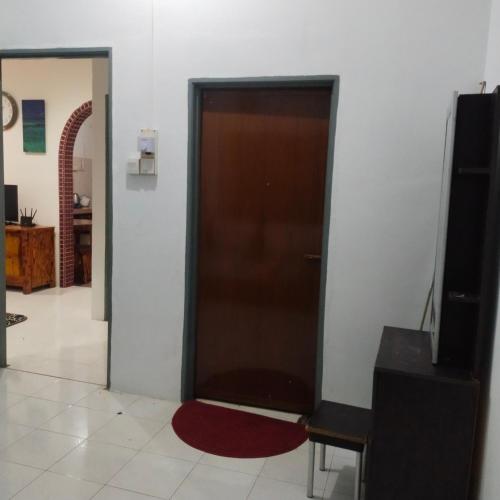 eine braune Tür in einem Zimmer mit einem roten Teppich in der Unterkunft Huda Homestay Bandar Tanah Merah in Distrikt Tanah Merah