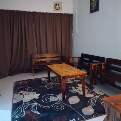 ein Wohnzimmer mit einem Tisch und einem Teppich in der Unterkunft Huda Homestay Bandar Tanah Merah in Distrikt Tanah Merah