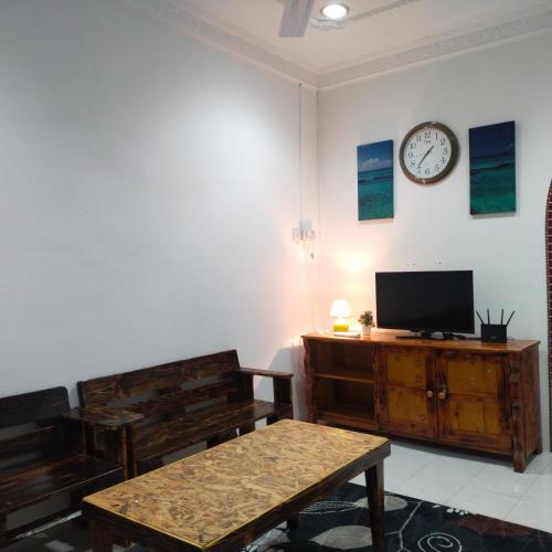 ein Wohnzimmer mit einem Tisch und einer Uhr an der Wand in der Unterkunft Huda Homestay Bandar Tanah Merah in Distrikt Tanah Merah