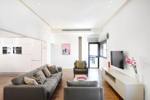a living room with a couch and a tv at Ester HaMalka by HolyGuest in Tel Aviv