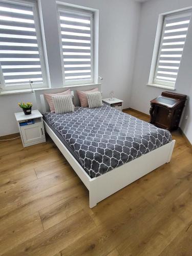 a large bed in a room with two windows at Apartament Jezioro w sercu Ostródy in Ostróda