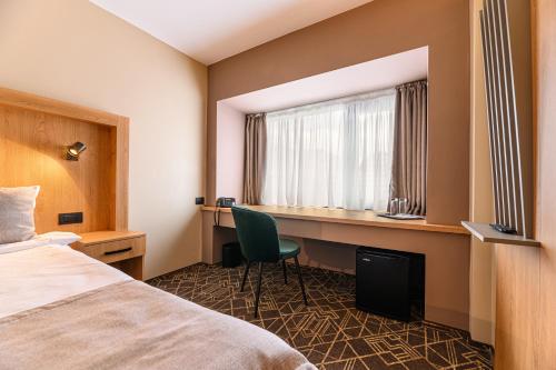 a hotel room with a bed and a desk and a window at HOTEL CENTRAL Pascani in Paşcani