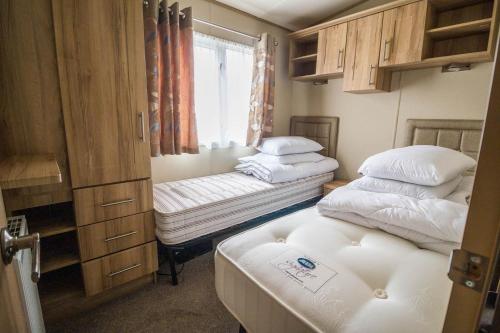 a small room with two beds and a window at 4 Berth Caravan With Decking And Wifi At Carlton Meres In Suffolk Ref 60010k in Saxmundham