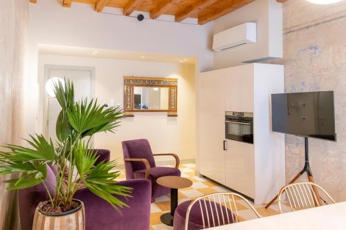 a living room with purple chairs and a tv at Palazzo Scappi Gardi Luxury Apartments in Bologna