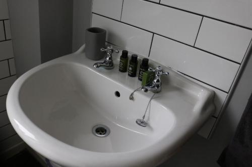 Un lavabo blanco en un baño con botellas. en Charming 2 Bed House - Family Friendly en Nottingham