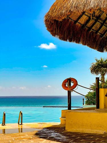 a beach with a straw umbrella and the ocean at Beachside Apartments Cancun in Cancún