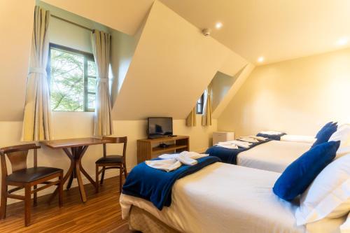 1 dormitorio con 2 camas, escritorio y mesa en Pousada La Toscana Campos do Jordão, en Campos do Jordão