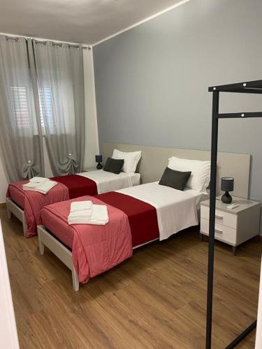 a bedroom with two beds with red and white sheets at M&G holiday house in Matera