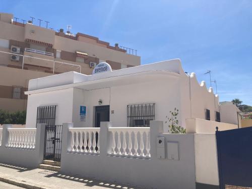 a white building with a white fence in front of a building at Hostal Avenida by Bossh! Hotels in Chipiona