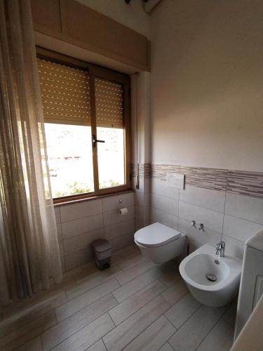a bathroom with a toilet and a sink and a window at Miky's House in Teulada