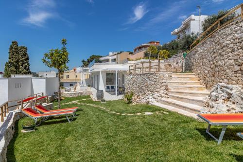 un jardín con 2 sillas y una pared de piedra en Ville Palà Luxury - Castro by HDSalento, en Castro di Lecce