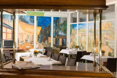 a restaurant with white tables and a painting on the wall at Apart' Hotel in Kehl am Rhein