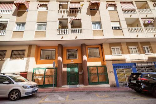 un edificio con coches estacionados frente a él en Apartamento compartido - SOLO EL DORMITORIO ES PRIVADO, en Torrevieja