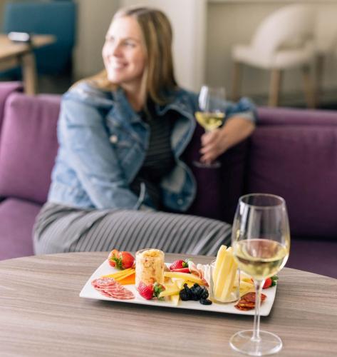a woman sitting at a table with a plate of food and a glass at Crowne Plaza Atlanta Perimeter at Ravinia by IHG in Atlanta
