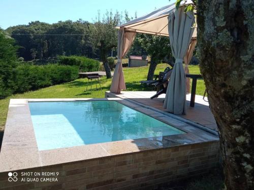 uma piscina com uma mesa e um guarda-sol em camino de santiago em Forcarei