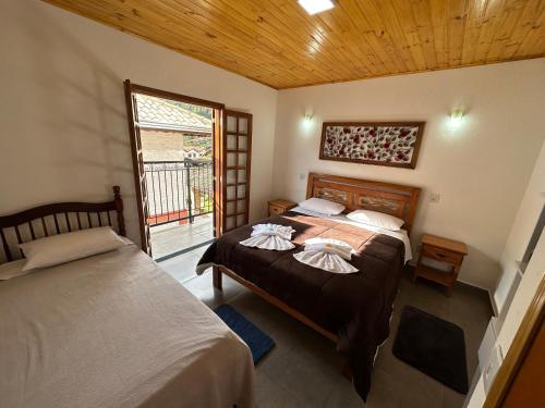 two beds in a room with a window at Pousada Requinte da Serra in Monte Verde