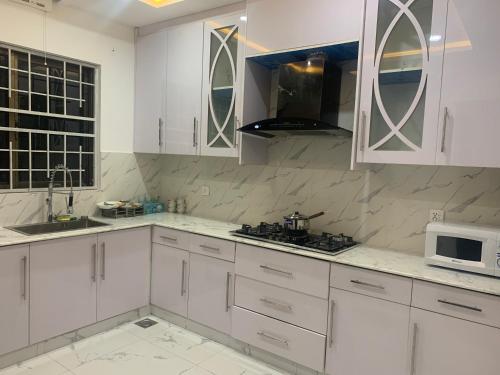 a white kitchen with white cabinets and a microwave at Bahria Residency 1 in Islamabad