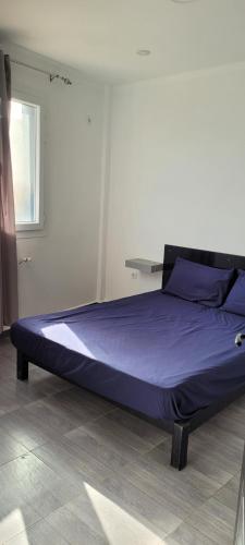 a bed in a room with purple sheets and a window at Immeuble Thala Tigzirt appart 70m in Tigzirt