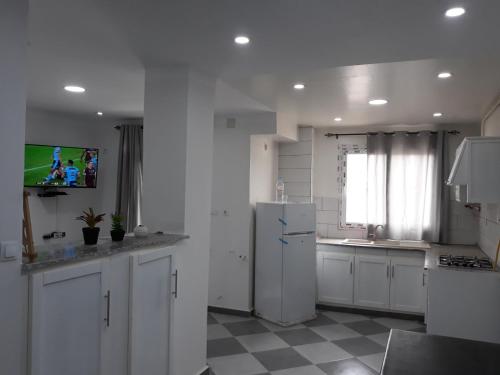 a kitchen with white cabinets and a white refrigerator at Immeuble Thala in Tigzirt