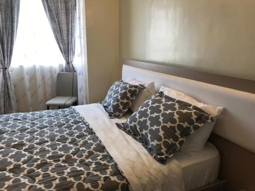 Maliaways Comfy Airbnb-Jkia في نيروبي: غرفة نوم بسرير ومخدات ونافذة