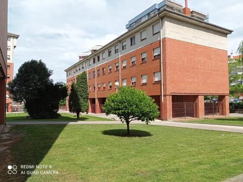 a large brick building with a tree in front of it at Apartamento céntrico in Avilés