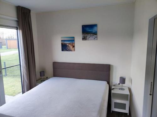 Schlafzimmer mit einem großen weißen Bett und einem Fenster in der Unterkunft Chalet Seepark Süsel in Süsel