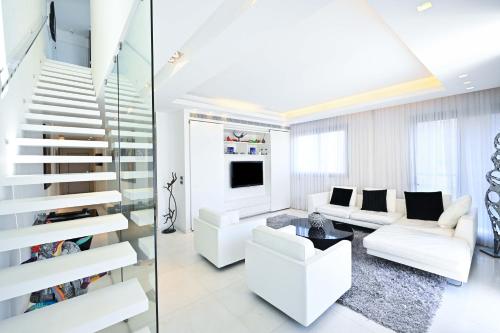 a living room with white furniture and a staircase at Luxe 3BR Penthouse w Jacuzzi&Parking&Mamad by HolyGuest in Tel Aviv