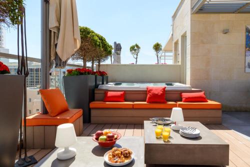 a patio with a couch and a table on a balcony at Luxe 3BR Penthouse w Jacuzzi&Parking&Mamad by HolyGuest in Tel Aviv