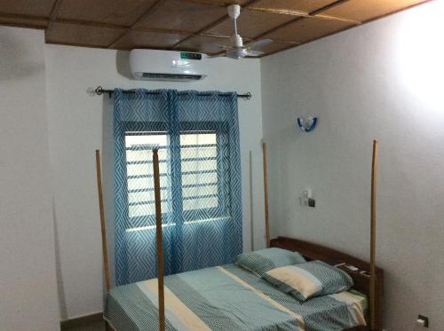 a bedroom with a bed with a blue curtain and a window at LES RÉSIDENCES SOHA in Cotonou