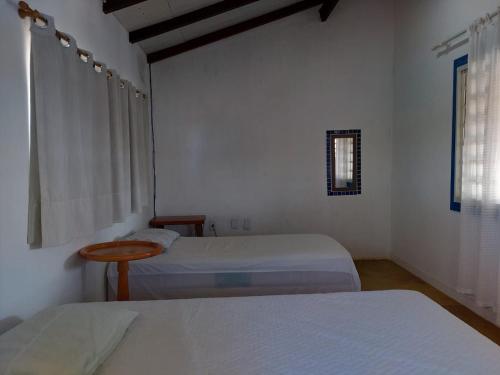 a white room with two beds and a window at Estância Casa Branca Corumbá IV MDPF in Luziânia