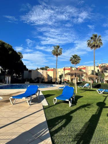 two blue chairs sitting on the grass near a swimming pool at Art-Apart Caronte in Riviera del Sol, Mijas Costa in Mijas Costa