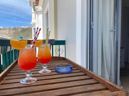 ナザレにあるApartamentos Carbel Marの木製テーブル、バルコニーでのカクテル2杯