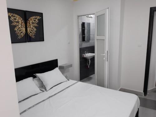 een witte slaapkamer met een bed met een vlinder aan de muur bij Immeuble THALA in Tigzirt