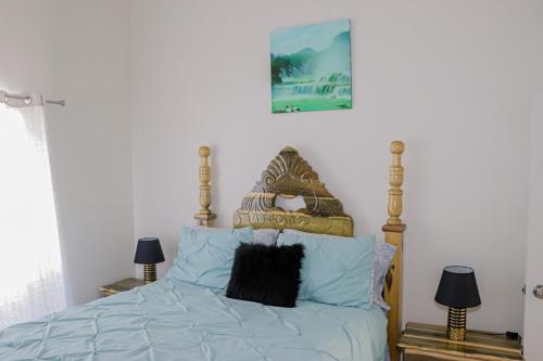een slaapkamer met een bed met blauwe lakens en 2 lampen bij Little Paradise in Discovery Bay