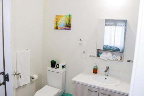 a white bathroom with a toilet and a sink at Little Paradise in Discovery Bay