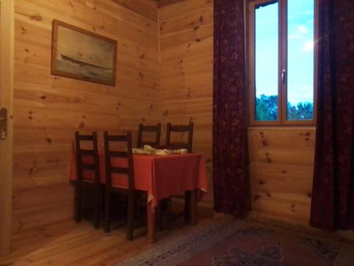 ein Esszimmer mit einem Tisch, Stühlen und einem Fenster in der Unterkunft Gîte l'appel de la Forêt in Betplan