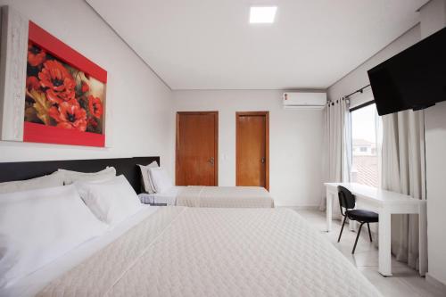 a hotel room with two beds and a desk at Hotel Kanaan in Pimenta Bueno