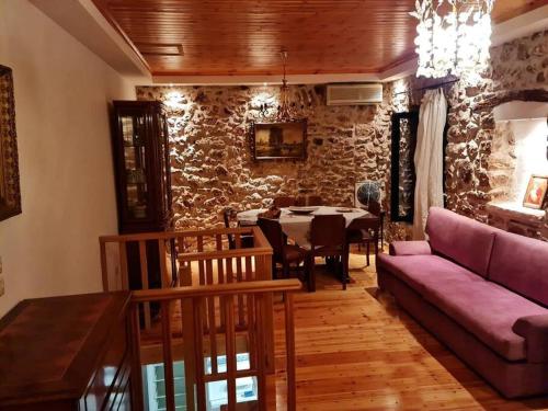 a living room with a purple couch and a table at Πέτρινο εξοχικό στο Δάρα in Daras