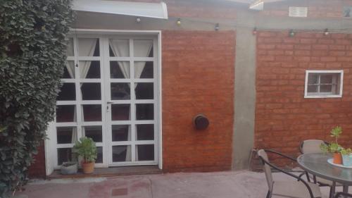een patio met een witte deur en een tafel en een bakstenen muur bij Monoambiente interno en Trelew in Trelew