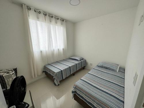 a bedroom with two beds and a window at Apartamento á 300 metros da praia de Itaparica e efrente o shoping bullevard in Vila Velha