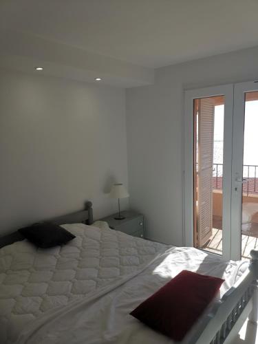 une chambre blanche avec un grand lit et un balcon dans l'établissement La baie d'Agay, à Saint-Raphaël