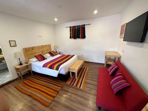 a bedroom with a bed and a red couch at CASA CRISTOBAL Siete Cuartones in Cusco