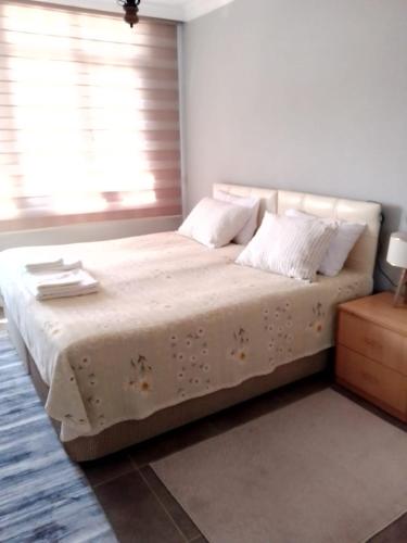 una camera da letto con un letto con lenzuola bianche e una finestra di Flat Close to Sea with Balcony in Seferihisar a Smirne