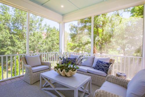 a screened porch with couches and a table at Whispering Palms in Seabrook Island