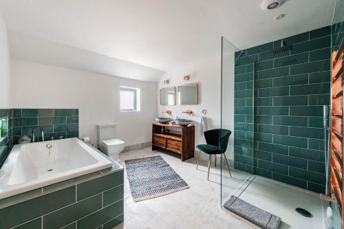 a bathroom with a tub and a shower with green tiles at Willow Barn in Haddiscoe