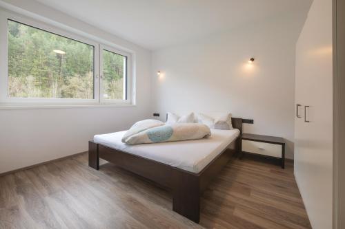 a white bedroom with a bed with a window at Apartment Eflin in Fulpmes